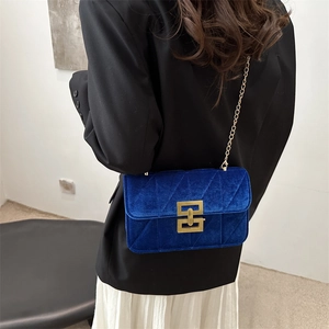 Quilted blue velvet crossbody bag with gold chain and metal lock shown on model
