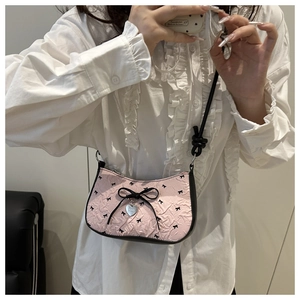 Détail du sac plissé rose avec un nœud noir et un pendentif coeur argenté