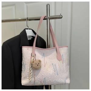Détail du sac cabas rose clair avec texture gaufrée, broderie ondulée et breloque ours