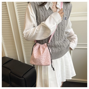 Détail du sac seau rose à fleurs porté en bandoulière avec une tenue d'été décontractée