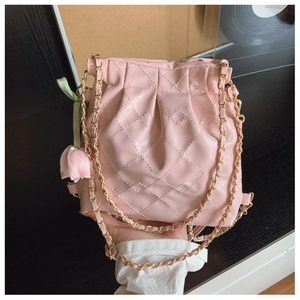Detailed view of pale pink quilted bucket bag with chain strap and tulip charm