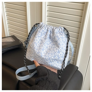 Détail du sac seau bleu clair avec broderie florale et cordon de serrage tissé