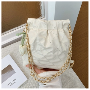 Close-up of quilted cream bucket bag with gold chain strap and tulip charm detail