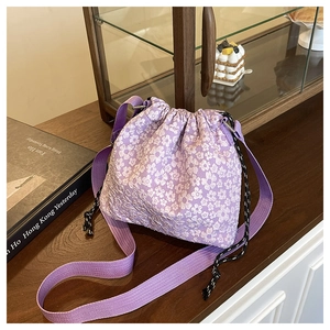 Détail du sac seau à fleurs violettes avec broderie, cordon et large bandoulière