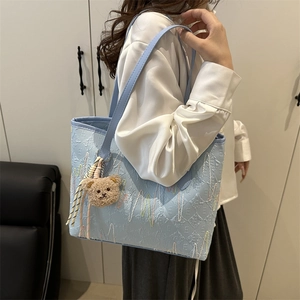 Sac cabas matelassé bleu clair avec broderie rayée, anses en cuir et petit pendentif ours