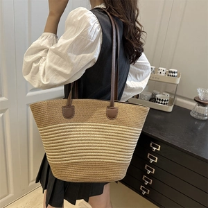 Large straw woven tote bag with brown leather shoulder straps for beach and summer travel