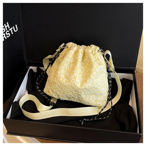 Détail du sac seau jaune avec texture jacquard florale et cordon de serrage à pois