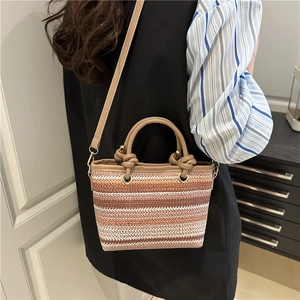 Colorful striped straw bucket bag with leather handle and knot detail on a model