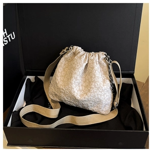 Vue de dessus d'un sac seau en dentelle beige avec cordon de serrage dans une boîte cadeau