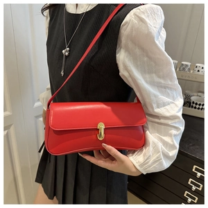 Detail of red leather baguette bag with shiny gold lock and sleek rectangular flap design