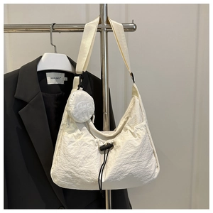 Detail der cremeweißen Hobo-Tasche mit plissierter Nylonstruktur und Kordelzugverschluss