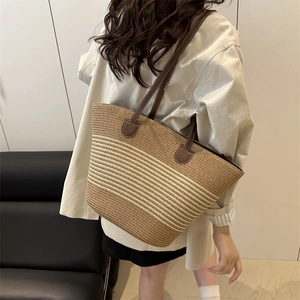 Large woven straw tote bag with brown leather straps and horizontal striped pattern