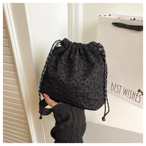 Détail du sac seau noir à cordon avec texture florale 3D et bandoulière en nylon