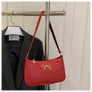 Detail of red pebbled leather shoulder bag with golden bow clasp and floral zipper charm