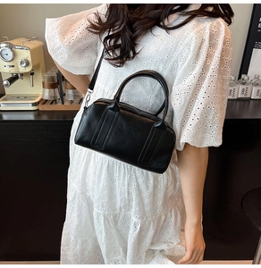 Chic black mini Boston bag styled with a white lace dress in an elegant cafe setting
