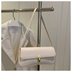 Detail of off-white baguette bag featuring golden U-shaped clasp and slim strap