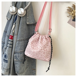 Vue détaillée du sac seau rose à fleurs avec cordon de serrage et bandoulière en toile