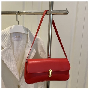 Detail of red leather underarm bag with gold clasp hanging on a metal hanger