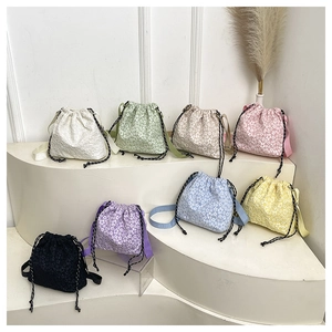 Détail de huit sacs seaux à fleurs colorés avec cordon de serrage sur des marches blanches