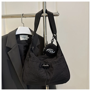 Detail der schwarzen Nylontasche mit Kordelzug, breitem Gurt und Mini-Münzfach