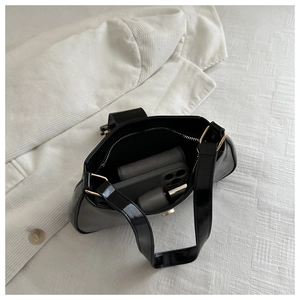 Interior view of black patent leather shoulder bag with gold hardware and daily essentials