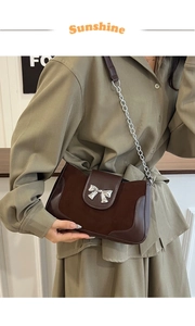 Detail of retro dark brown saddle bag with silver bow buckle and mixed leather textures