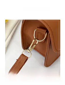 Close-up of golden metal hooks and D-ring on brown lychee grain leather shoulder bag