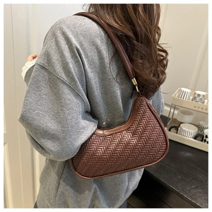 Close-up of brown herringbone woven leather on a half-moon hobo bag with gold metal hardware