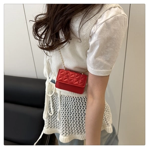 Detail of a mini red rainbow quilted crossbody bag with a delicate gold metal chain strap