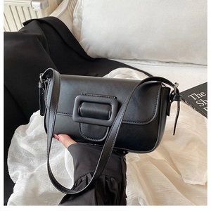 Détail d'un sac baguette en cuir noir avec une boucle carrée élégante et une bandoulière fine