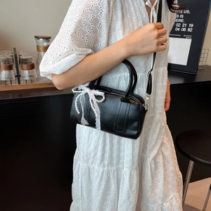 Elegant black Boston bag with lace bow and pearl handle for a stylish spring look