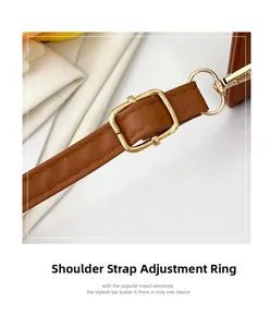 Close-up of brown leather bag strap with adjustable gold-toned buckle and D-ring
