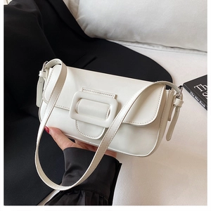 Gros plan du sac sous le bras crème avec grande boucle sur une veste de tailleur noire