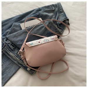 Detail of pink PU leather mini crossbody bag with heart pattern flap on denim fabric