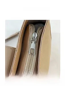 Detailed macro view of the smooth silver zipper and metal puller on khaki saddle bag