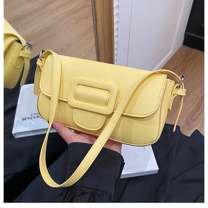 Detailed close-up of a bright yellow leather baguette bag with a decorative large buckle