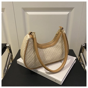 Detail of woven crescent hobo bag with brown trim on white book in minimalist setting