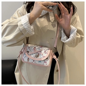 Close-up of pink bow and silver heart pendant on a sweet bear print crossbody bag
