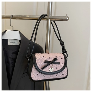 Detailed view of pink pleated shoulder bag with black bows and silver heart charm