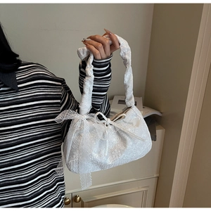 Close-up of white floral lace tote bag featuring a decorative bow and ruffled handle