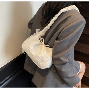 Close-up of white lace tote bag with bow detail and ruffled shoulder strap