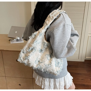 Détail d'un sac cabas en toile blanche avec imprimés papillons bleus et bords effilochés