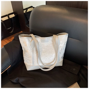 Close-up of white tote bag with silver ink textures and metal Fashion label detail