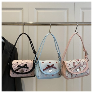 Detail of trendy crossbody bags featuring bow decorations and heart-shaped metal pendants