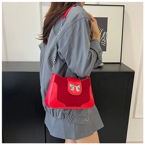 Detail of red saddle bag featuring mixed leather texture and silver bow accent
