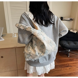Détail du cabas en toile blanche avec imprimés papillons bleus et bords effilochés