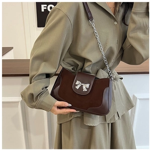 Detail of dark brown saddle bag with silver metal bow and mixed chain strap