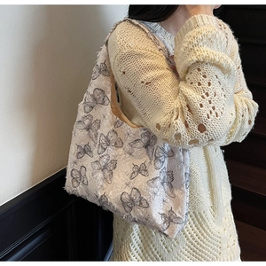 Détail du tissu jacquard à motif cœur et franges sur un sac cabas blanc