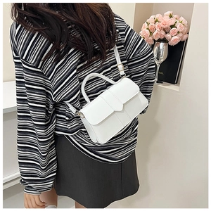 Détail du sac bandoulière en cuir blanc avec poignée et boucle dorée pour l'usage quotidien