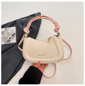 Detail of cream crescent hobo bag with pink knotted handle and gold logo branding